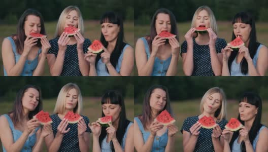 日落时分，三个年轻迷人的女性朋友在吃着西瓜，面带微笑。高清在线视频素材下载