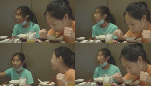 快乐的亚洲女孩与家人一起在餐厅吃面条、素喜烧、涮锅或火锅，生活方式理念。高清在线视频素材下载