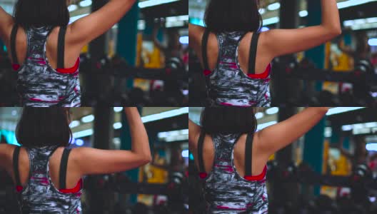 后视镜:年轻的亚洲女性在健身房里，在镜子前举起哑铃，锻炼肌肉(背部和二头肌)，锻炼力量，身体健康和结实。高清在线视频素材下载