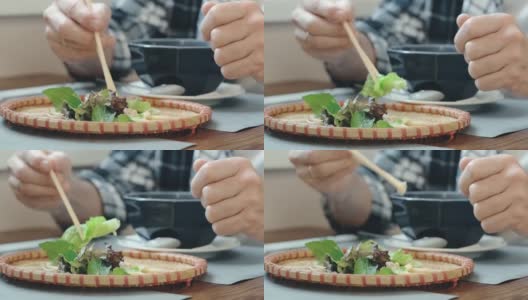 在一家亚洲餐馆里，一名男子用筷子吃生菜叶子高清在线视频素材下载