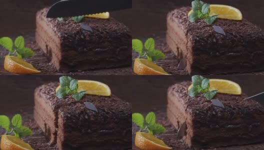 切一片用鲜橙和薄荷装饰的巧克力蛋糕。极端特写镜头高清在线视频素材下载