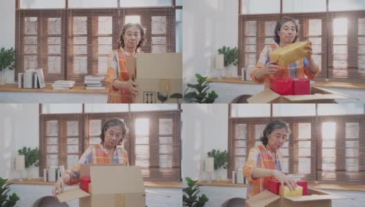 亚洲高级妇女打开纸板箱从网上购物和检查商品里面高清在线视频素材下载