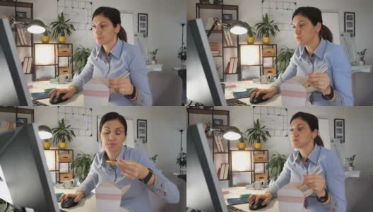 中年女商人吃着中餐，在办公室工作——慢镜头高清在线视频素材下载