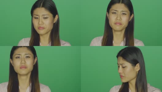 美丽的亚洲女人看起来沮丧，在一个绿色屏幕的工作室背景高清在线视频素材下载