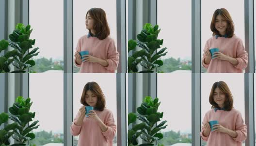 年轻美丽的亚洲女人喝咖啡，透过窗户与城市的看法与幸福，人们的生活方式高清在线视频素材下载