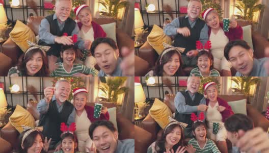 笑容满面的亚洲大家庭和孩子们坐在客厅的沙发上一起在手机上自拍视频，快乐的父母和孩子们在家里用智能手机进行有趣的视频通话高清在线视频素材下载