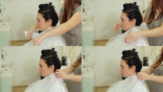 在一家发廊里，女发型师正在为一个年轻女孩的脖子固定衣领。高清在线视频素材下载