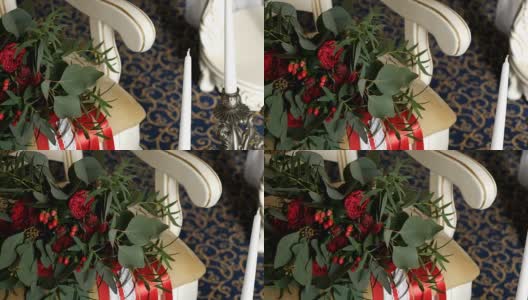 美丽的婚礼组成组成的蜡烛和美丽的红玫瑰花束和牡丹在红色丝带躺在复古扶手椅。高清在线视频素材下载