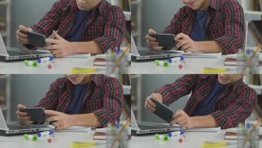 懒惰的男性青少年在智能手机上玩手机游戏，而不是做作业高清在线视频素材下载