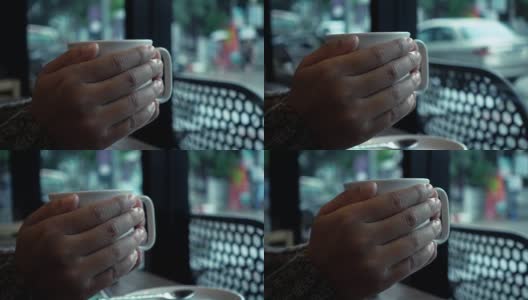 女人手捧着一杯咖啡在咖啡馆在雨天高清在线视频素材下载