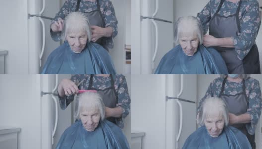 手持拍摄的一个年长的白人妇女在家里理发由专业护理发型师高清在线视频素材下载