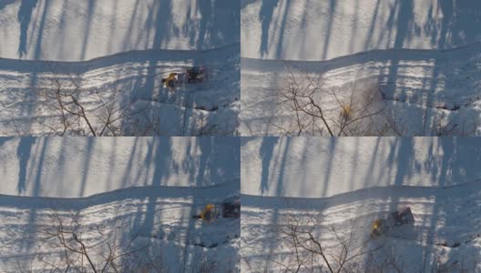 一名成年男子在一场冬季降雪后用除雪机清理车道上的积雪。鸟瞰无人机正上方的慢动作视频。高清在线视频素材下载