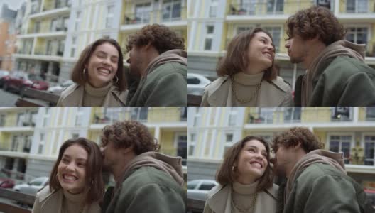 一对快乐的夫妇在城市街道上欢笑。男人对女人低声说着有趣的故事。高清在线视频素材下载