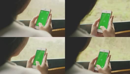 在火车上移动到其他地方时，智能手机上的绿色屏幕上的亚洲妇女的手的特写-色度键高清在线视频素材下载