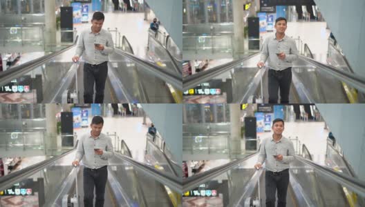 一名年轻人拿着行李箱站在人行道上，一边使用智能手机。高清在线视频素材下载