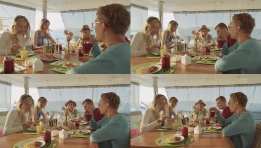 一群年轻漂亮的人在游艇上吃健康早餐，他们在聊天。他们的桌上有各种各样的蔬菜和冰沙。海是背景。高清在线视频素材下载