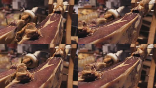 Jamon塞拉诺。传统西班牙火腿在市场上收市。桌上的猪腿火腿。餐厅内部的美食肉。整个火腿放在架子上。摄像机从左向右移动高清在线视频素材下载