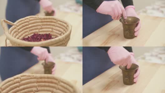 一个篮子的特写侧视图，满是干花。镜头移动，展示了女孩如何用杵将干燥的玫瑰花瓣磨成粉末。高清在线视频素材下载