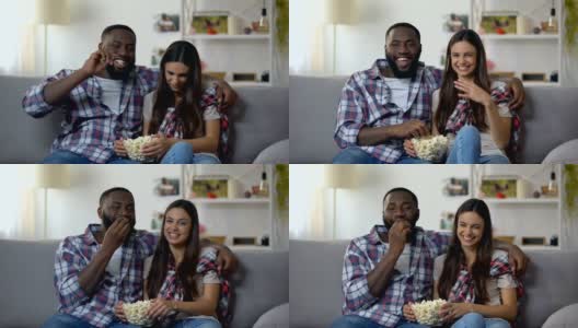 不错的多民族夫妇与流行玉米看喜剧秀，笑，放松高清在线视频素材下载