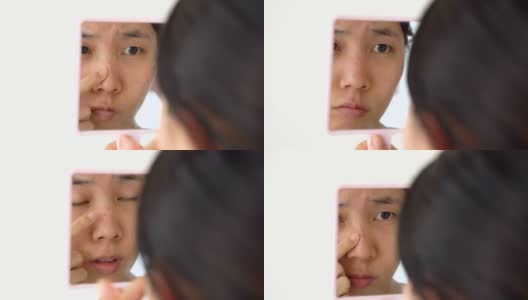 亚洲妇女观察她的青春痘通过手镜高清在线视频素材下载
