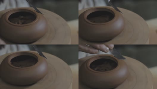 陶工师傅用木柄上的金属铲，用宜兴陶土制作茶壶。茶道用手工陶壶。褐色陶器茶壶。4 k的视频。59.94帧/秒高清在线视频素材下载