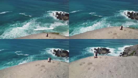 一架无人机拍摄到一对夫妇站在悬崖边欣赏风景。俯瞰印尼龙目岛丹戎安海滩。绿松石色的水。幸福和和睦高清在线视频素材下载