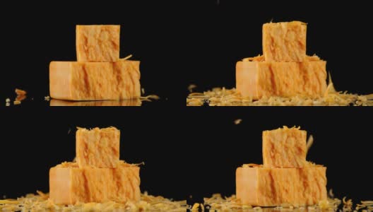 小块磨碎的切达干酪落在大块上。高清在线视频素材下载