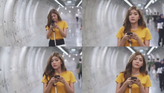 年轻美丽的亚洲女人用智能手机导航走在地铁站里。有魅力的女孩用手机和互联网进行社交媒体或在线信息。无线技术与城市生活理念。高清在线视频素材下载