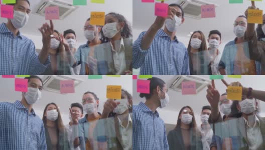 小组头脑风暴的亚洲人把便利贴贴在窗户上。团队合作的商务人士戴上口罩，可以防止新冠病毒感染，在办公室讨论和分享解决问题的想法。高清在线视频素材下载