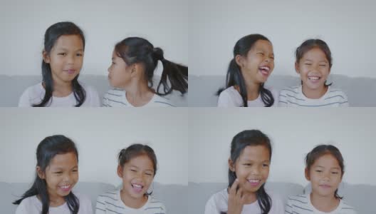 两个亚洲小女孩的肖像看着相机，微笑着，在客厅幸福地一起笑。慢动作50 FPS。高清在线视频素材下载