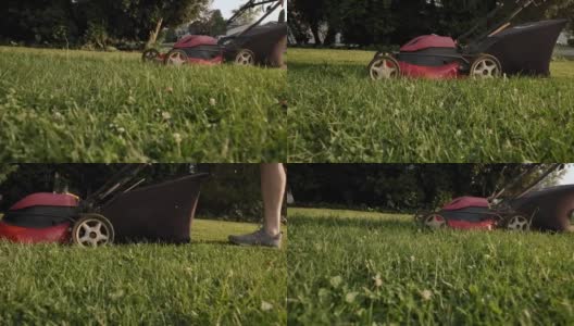 男子在操场秋千附近的院子里用割草机割草。慢镜头futage高清在线视频素材下载