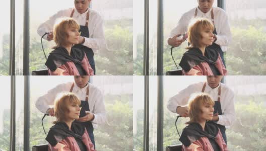 美发师在美容院用小吹风机为漂亮的白人女性做头发。高清在线视频素材下载