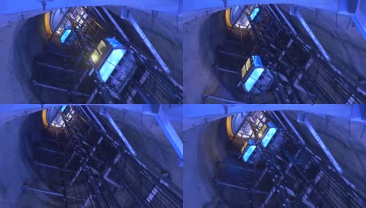 在竖井里上下爬的人乘坐的电梯被蓝色的灯光照亮高清在线视频素材下载