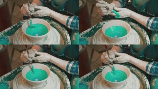 一个年轻女人的手用陶轮做陶器，在现成的碗上涂上釉。高清在线视频素材下载