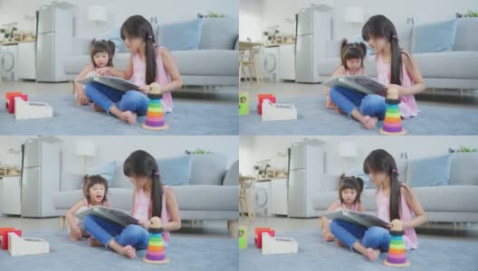 亚洲大妹展示老专辑向小妹追忆往事。可爱的小女孩坐在沙发上，翻着相册，享受回忆照片中的关系高清在线视频素材下载
