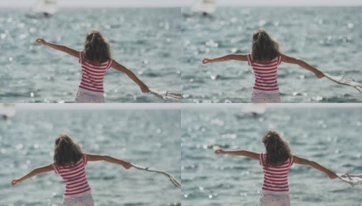 慢动作:拿着丝巾在海边迎着风的女孩高清在线视频素材下载