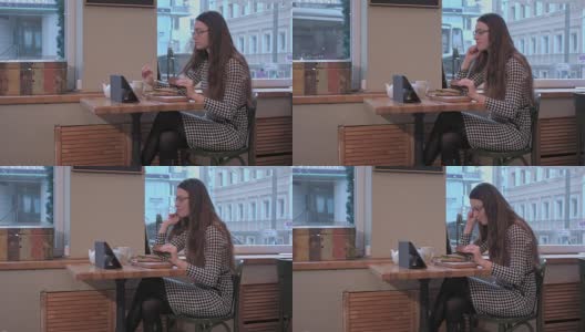 商务女士一边在咖啡厅吃三明治一边用平板电脑高清在线视频素材下载