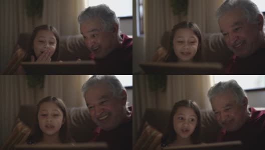 祖父和孙女正在用家里的平板电脑进行视频通话高清在线视频素材下载