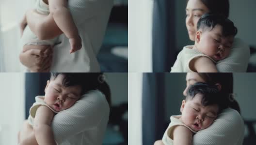 美丽的母亲抱着可爱的婴儿在家里睡觉高清在线视频素材下载