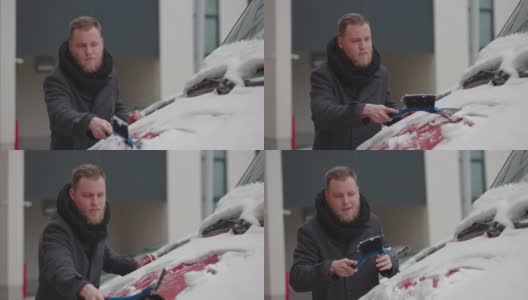 在用刨冰器清理车上积雪时，一名男子向手中吹气，这样他就能保持温暖高清在线视频素材下载