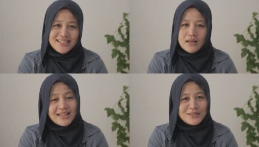 亚洲穆斯林妇女戴着头巾对着摄像头说话，伊斯兰阿拉伯妇女POV对着摄像头说话，进行视频电话会议，工作面试记录，在办公室进行在线研讨会演示高清在线视频素材下载
