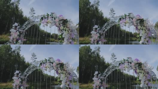 美丽的婚礼拱门上装饰着鲜花和其他装饰品。一阵微风吹来。四周都是美丽的大自然高清在线视频素材下载