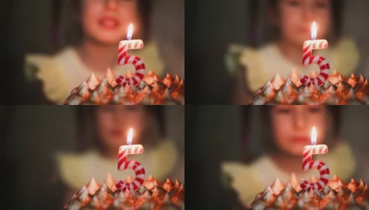 女孩看着蛋糕上写着数字5的燃烧的蜡烛，许了一个愿。生日，五周年，五年，烛火，橙火。孩子们的节日。特写镜头高清在线视频素材下载