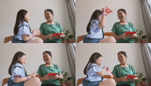 中国新年期间，亚洲孙女在卧室问候和接受祖母的中国新年红包高清在线视频素材下载
