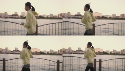 日落时分的东京，一名女子在河边奔跑高清在线视频素材下载