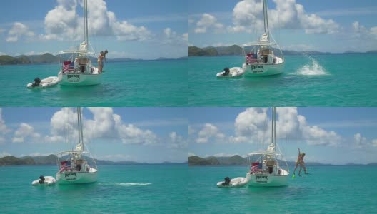 一对夫妇从加勒比海的一艘帆船上跳下的视频高清在线视频素材下载