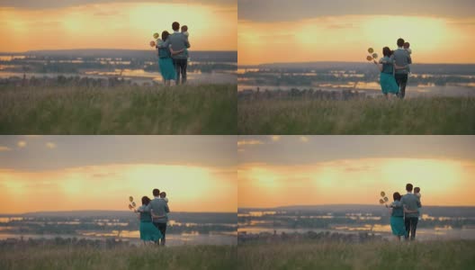 一家人三人在大自然中休息，爸爸妈妈和儿子去拥抱，橙色的夕阳高清在线视频素材下载