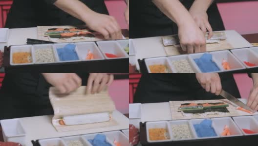 厨师的手在餐具垫上卷寿司，把寿司卷里外包起来高清在线视频素材下载