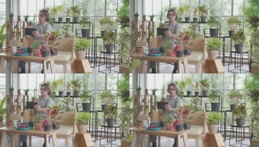 在新冠疫情期间，一名男子正在用平板电脑给自家花园里的植物拍照，这是一种快乐的居家园艺爱好高清在线视频素材下载