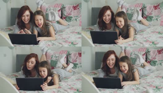 快乐可爱的女儿和年轻的母亲躺在舒适的卧室床上用笔记本电脑与父亲或祖母进行在线视频通话高清在线视频素材下载